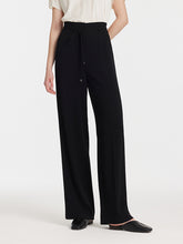 A lady wears high-waisted black pants.